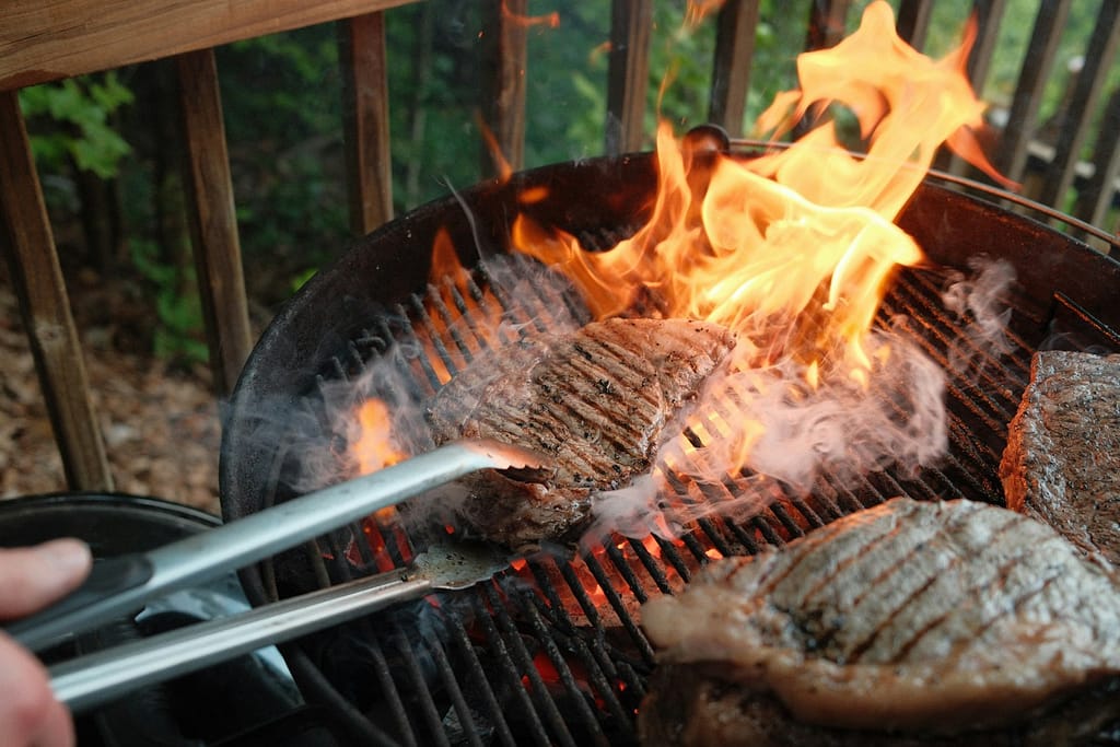Steak na grilu otáčený kleštěmi