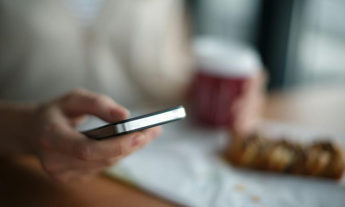 Host v kavárně s mobilním telefonem
